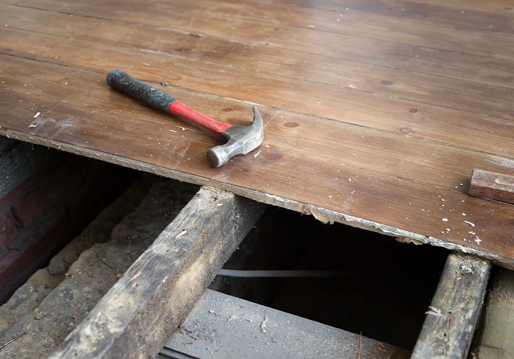 Suspended timber floor with some of floor boards lifted showing cavity beneath